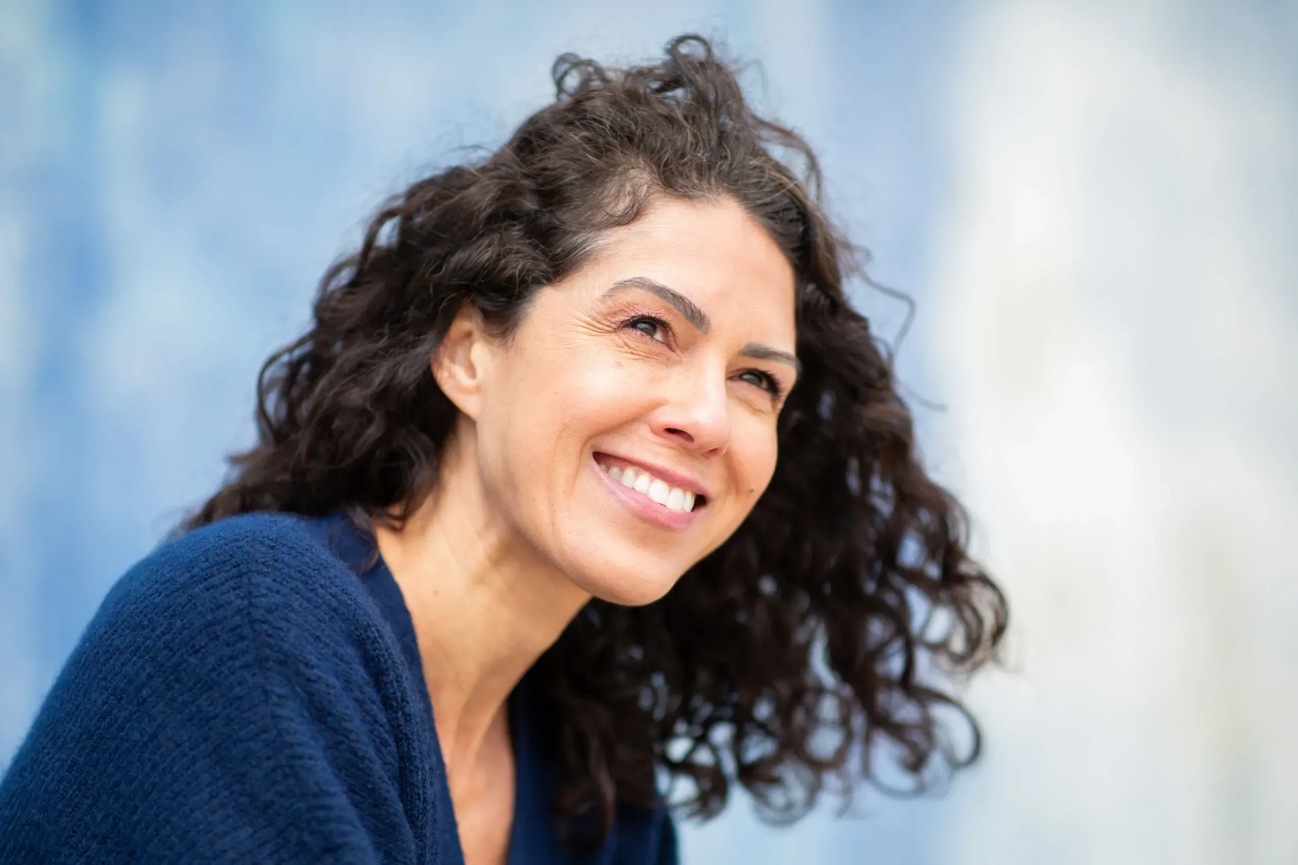 Smiling woman with curly hair representing wellness and chiropractic care at Bensa Chiropractic in Bradenton